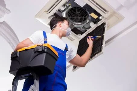 Technician servicing a ceiling-mounted HVAC unit
