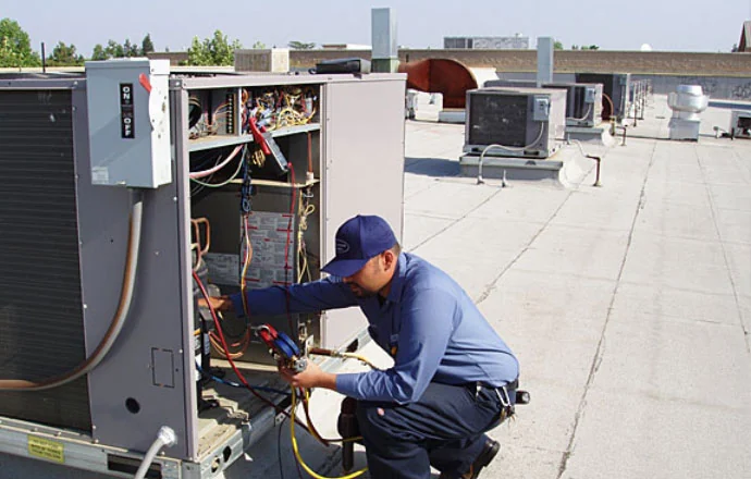Technician repairing rooftop heating and cooling equipment