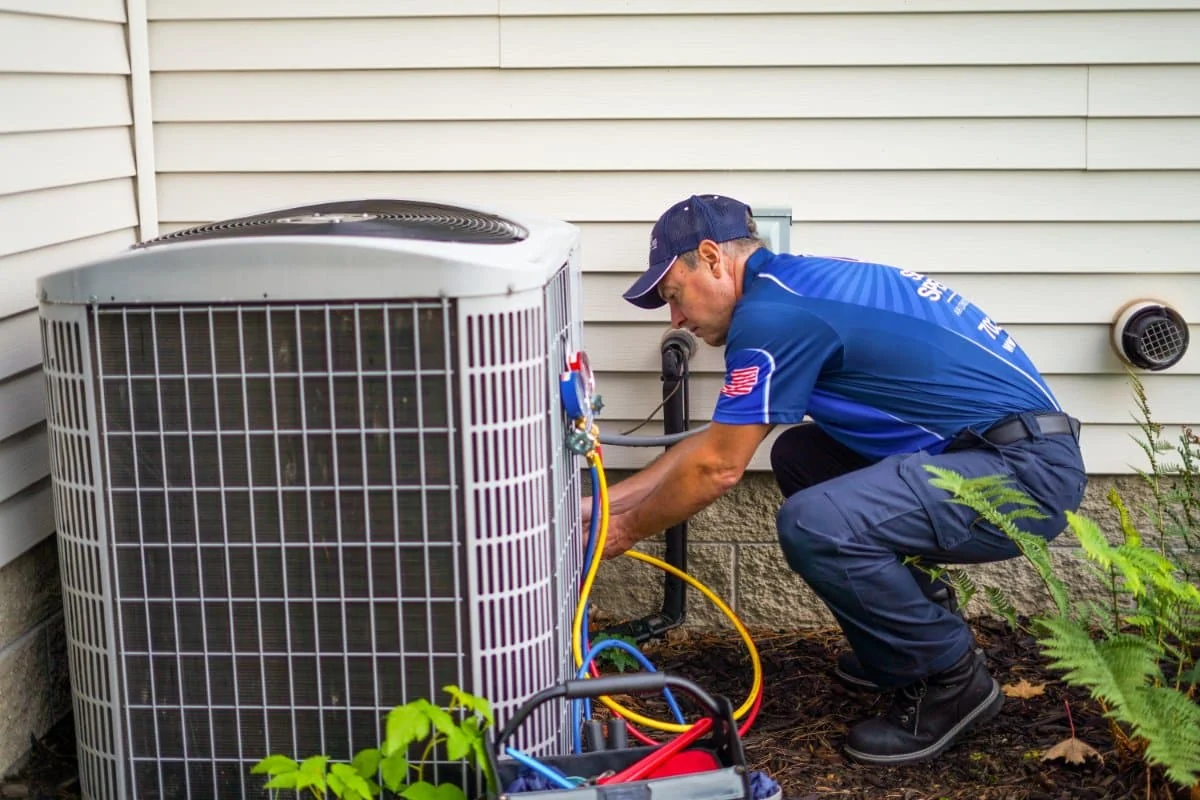HVAC technician servicing a residential air conditioning condenser